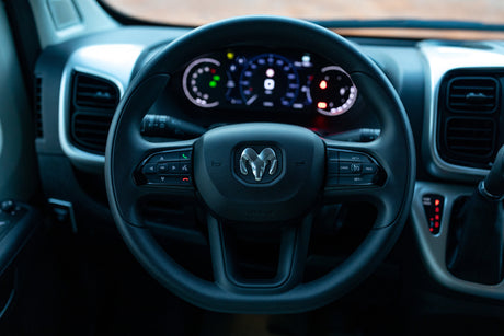 Ram steering wheel and illuminated digital dashboard in an RV rental, showing vehicle controls and gauges.