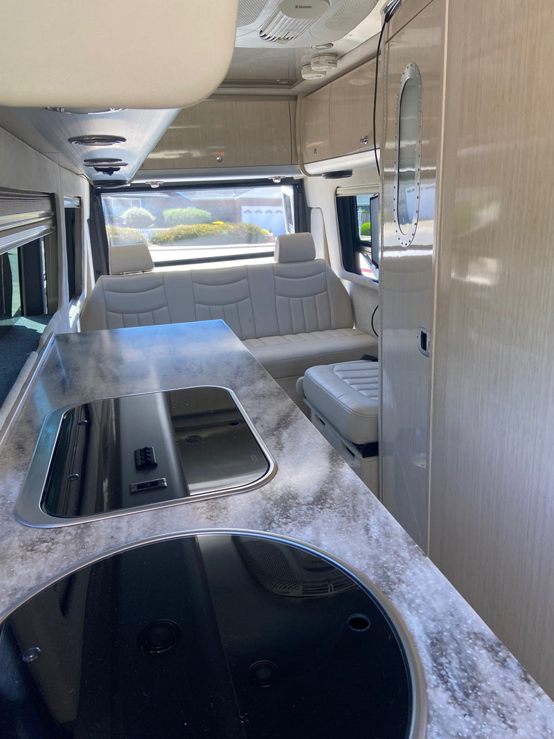  spacious cockpit with light-colored captain's chairs and dashboard.|Compact RV rental bathroom with sink — photo 9