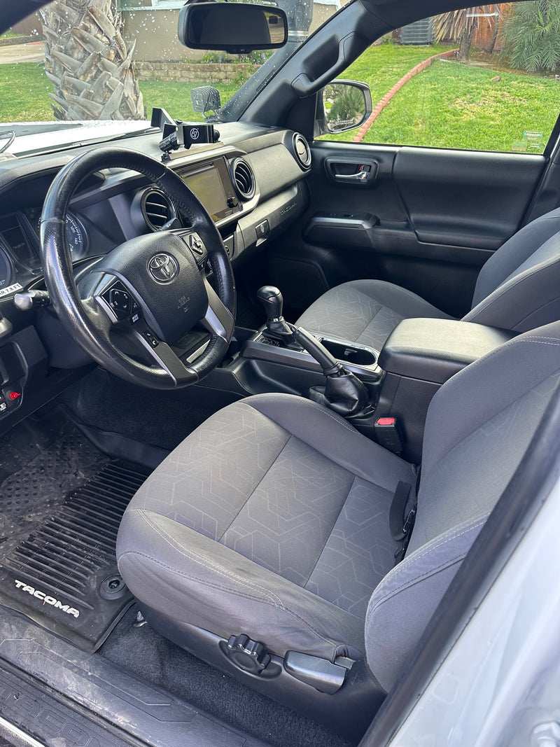 Spacious gray vehicle interior with steering wheel & dashboard. View of green yard outside. Perfect for trips, possibly with an rv rental. — photo 12