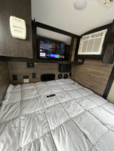 This RV rental offers a compact bedroom with a comfy bed, TV, AC, and climate controls for a cozy stay.