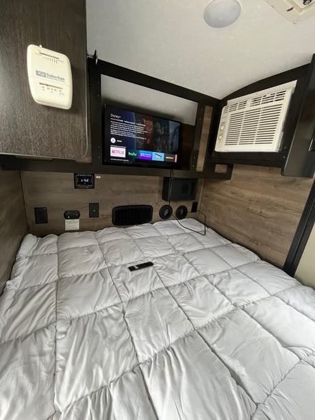 This RV rental offers a compact bedroom with a comfy bed, TV, AC, and climate controls for a cozy stay.