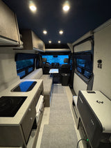 Modern RV rental interior with kitchenette, bench seating, and Dometic fridge for comfortable travel.