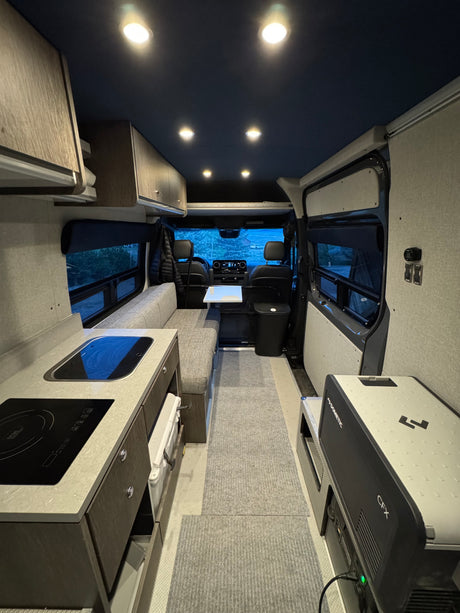 Modern RV rental interior with kitchenette, bench seating, and Dometic fridge for comfortable travel.