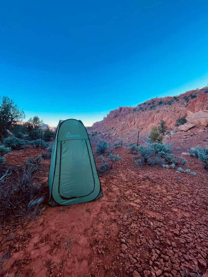 A green Wolfwise privacy tent in a red rock desert under a clear blue sky. Ideal for an rv rental adventure or remote camping. — photo 15