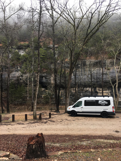 Van Life KC camper van rental at a rocky, forested campsite. An ideal RV rental for exploring nature's beauty.