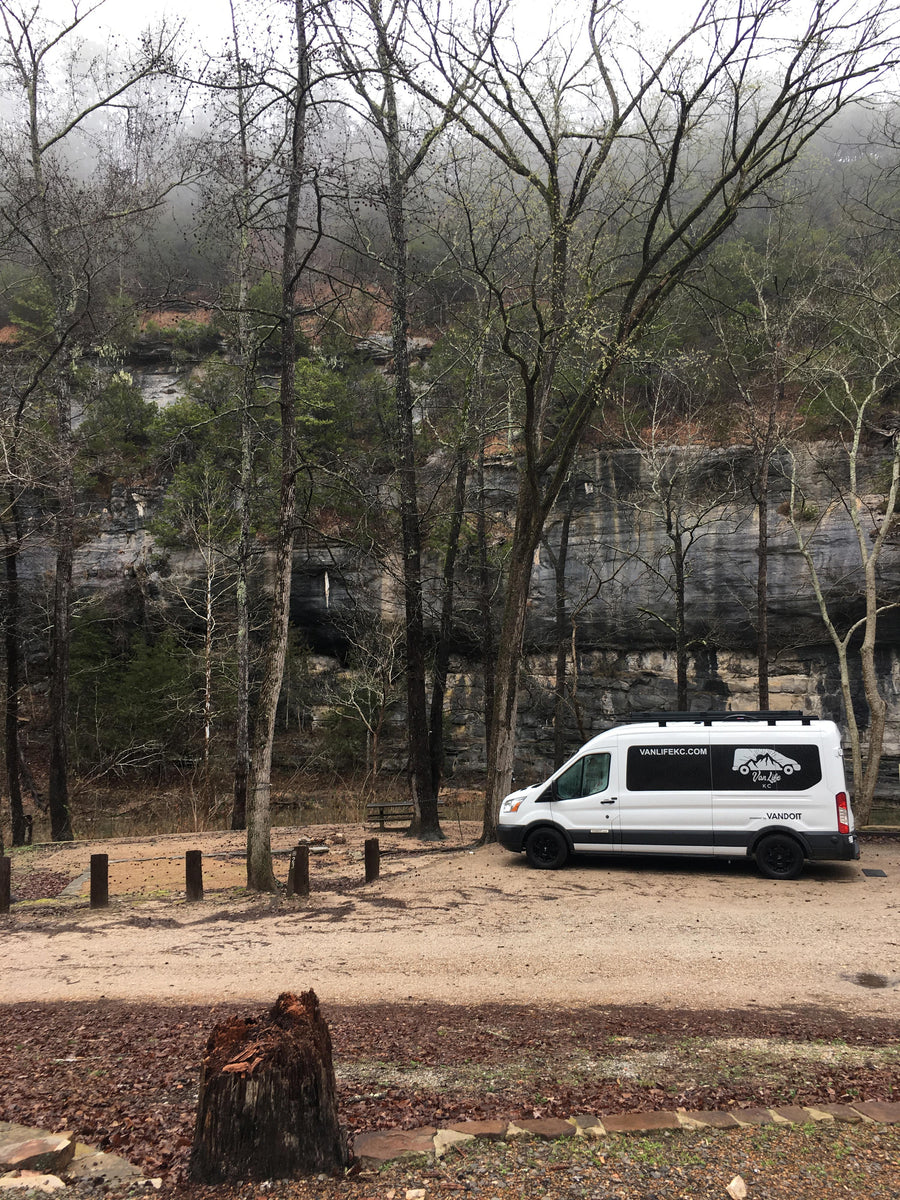 Van Life KC camper van rental at a rocky, forested campsite. An ideal RV rental for exploring nature's beauty.