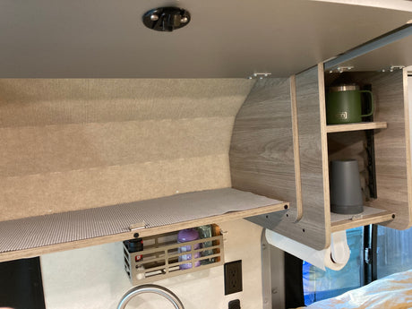 Compact and organized rv rental interior with overhead cabinets, efficient shelving, and a hanging storage basket.