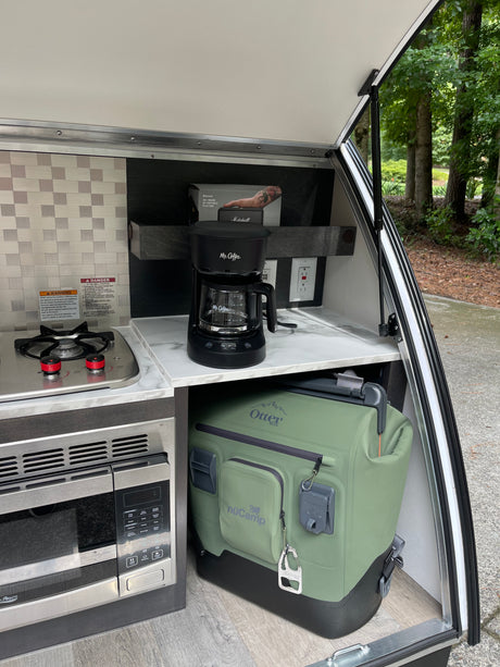 RV rental galley with essentials: stove, microwave, Mr. Coffee, and an OtterBox cooler for comfortable camping.