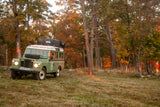 This classic green Land Rover, fitted with a roof tent, is an ideal RV rental for autumn adventures.
