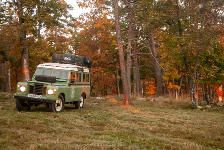 This classic green Land Rover, fitted with a roof tent, is an ideal RV rental for autumn adventures.