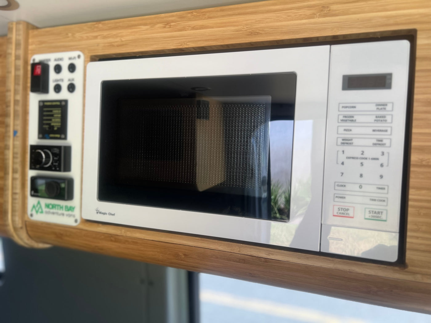 Compact Magic Chef microwave and control panel within a sleek bamboo wood interior of an RV rental. — photo 10