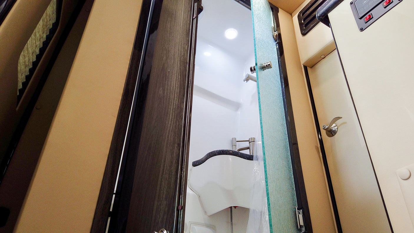 Compact RV bathroom with shower and sink, seen through an open door. Ideal for rv rental adventures.