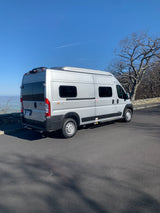 A silver Winnebago Solis RV rental is parked with a scenic valley view on a clear day, ideal for adventure.