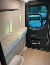 Inside an RV rental, a modern camper van features a comfy bench, rear window with outside view, and convenient storage net.