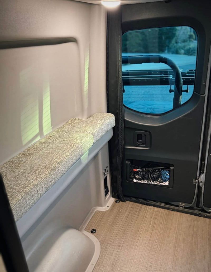 Inside an RV rental, a modern camper van features a comfy bench, rear window with outside view, and convenient storage net. — photo 15