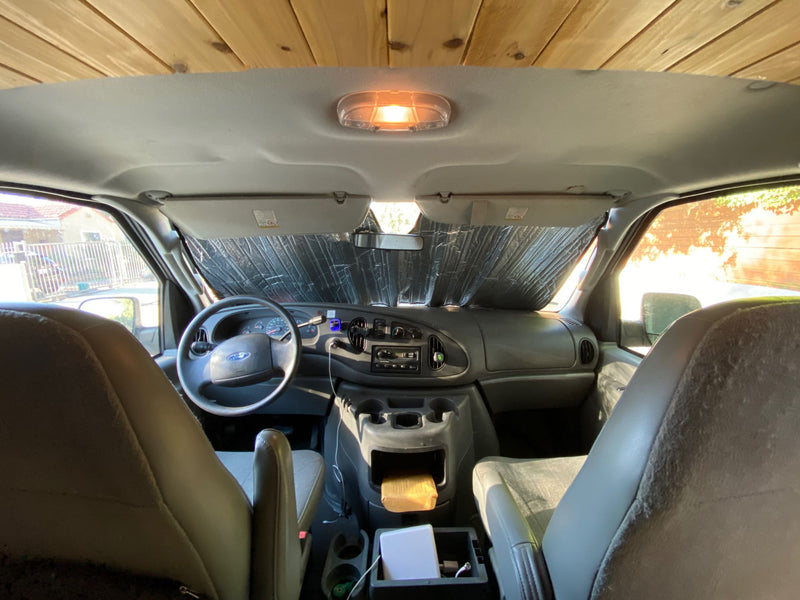  parked on a sunny dirt road amidst green mountains under a clear blue sky.|White passenger van — photo 5