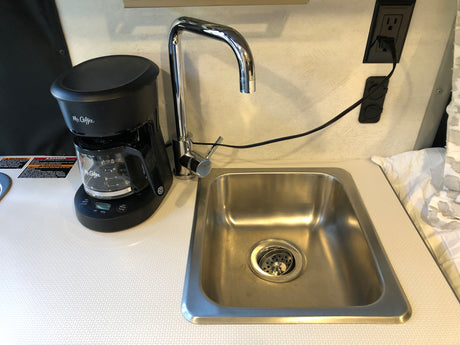 Inside an RV rental, compact kitchenette with Mr. Coffee maker, stainless steel sink, and chrome faucet.