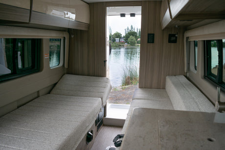 Enjoy the scenic lake view from inside this cozy RV rental, featuring comfortable bench seating and overhead storage.
