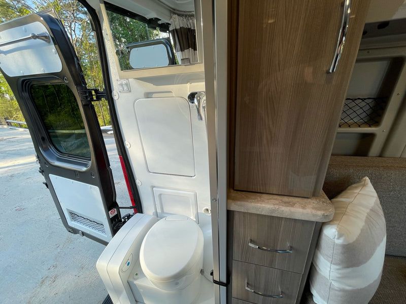 This rv rental interior features a compact bathroom with toilet, shower, and storage cabinetry, ready for adventures. — photo 14