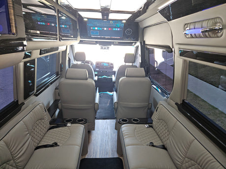 Spacious luxury RV rental interior with plush seating, entertainment screens, and wood floors for comfortable travel.