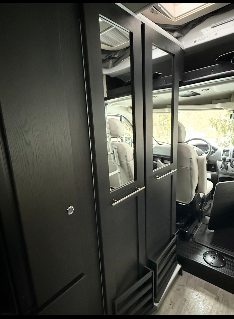 Sleek RV rental interior with dark wood cabinets & mirrored panels, reflecting the front seats of this modern camper van. — photo 8