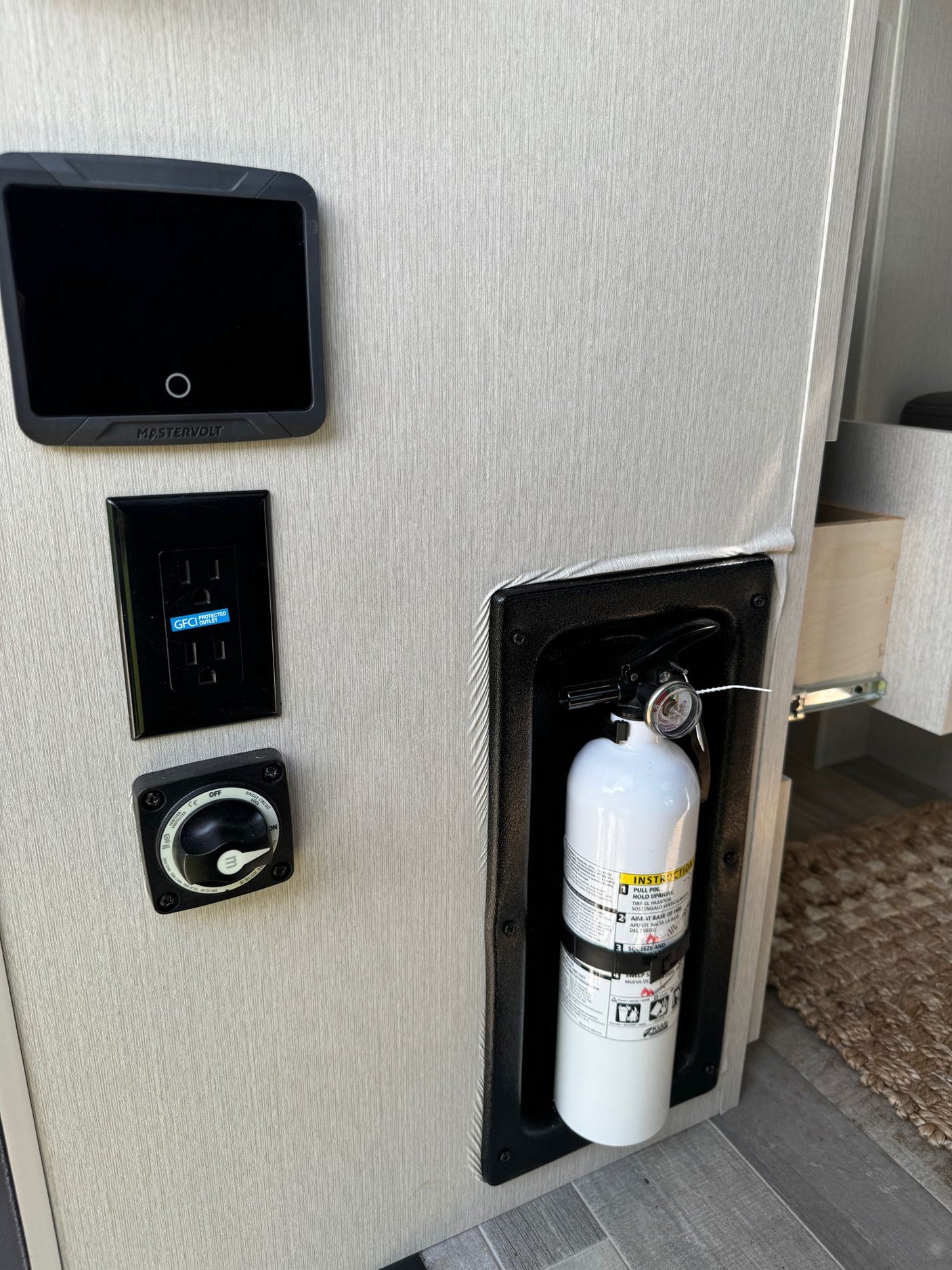 RV rental interior: Mastervolt power monitor, GFCI outlet, battery switch, & fire extinguisher for safety.