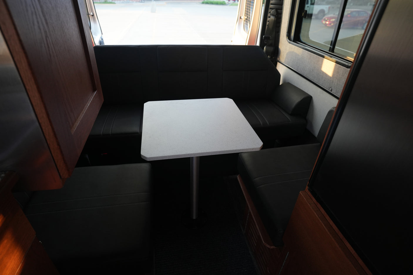 Inside this RV rental, find a compact dining area with a white table and dark cushioned benches. Perfect for travel.