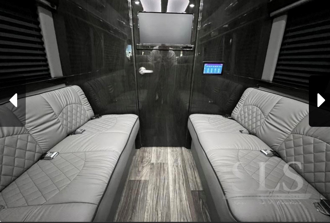  quilted leather seats and elegant wood-style flooring.|Experience luxury in this RV rental's lavish interior: light gray captain's chairs with tables & footrests for premium travel.|Luxury RV rental interior featuring facing gray benches — photo 4