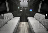 Luxury RV rental interior featuring facing gray benches, wood floor, and a mounted screen for travel comfort.