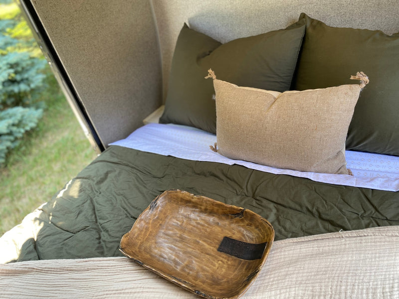 Inside your RV rental: a plush bed with olive green sheets, decorative pillow, and unique wooden bowl, overlooking nature. — photo 7