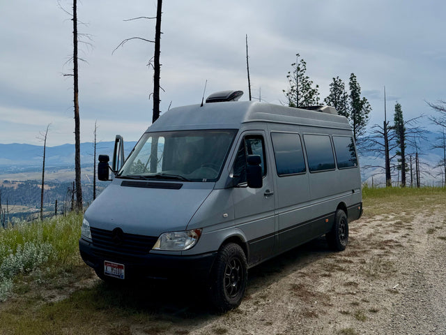 Grey camper van parked on a scenic Idaho overlook with mountain views, perfect for an RV rental adventure.