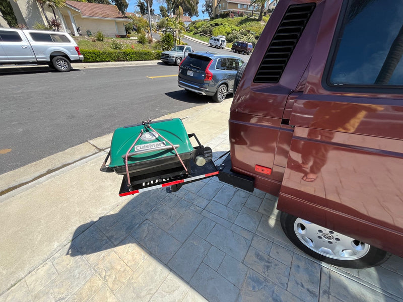  and tied-back window curtains.|An RV rental's stainless steel Westfalia kitchenette features an open two-burner stove and sink — photo 13