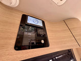 RV rental's smart control panel: 100% battery, 73°F temp, furnace, hot water, awning, and LED lights displayed on a wood wall.