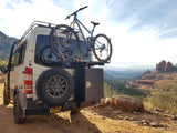 White Mercedes Sprinter rv rental van with a mountain bike & spare tire, parked at a breathtaking red rock overlook.