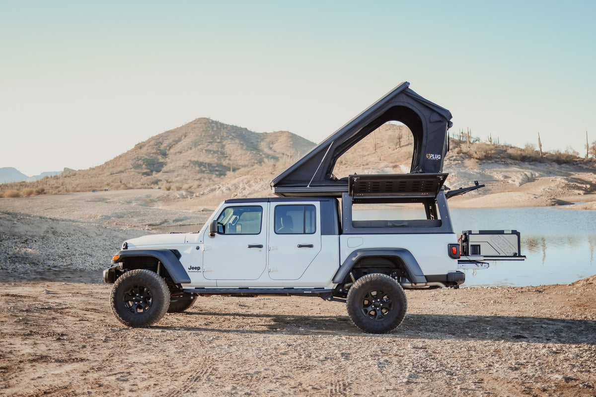 White Jeep Gladiator with rooftop tent & ARB fridge, an ideal RV rental for overlanding by the lake.