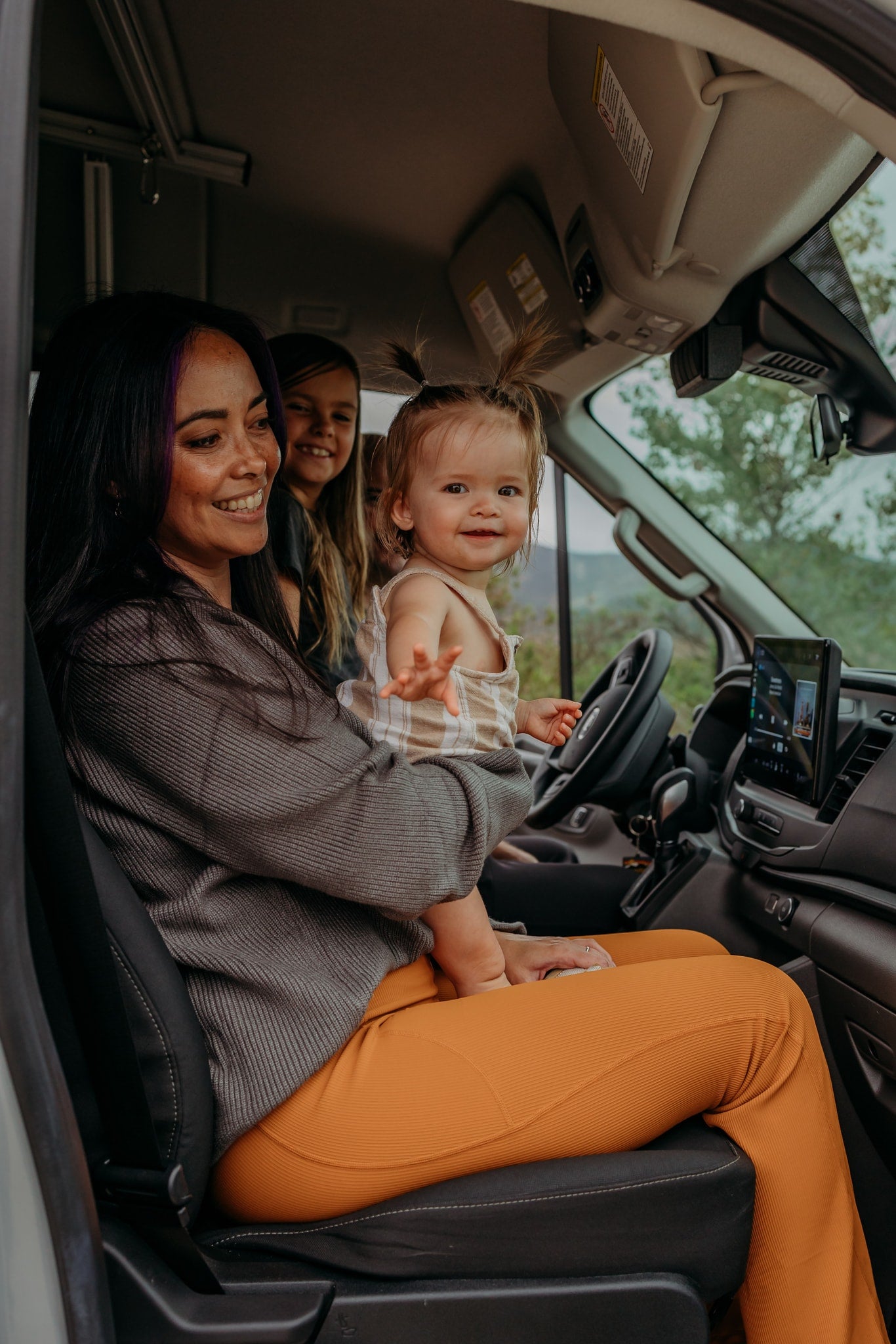 Smiling mom holds a baby with another child in their cozy rv rental, ready for family adventures. — photo 2