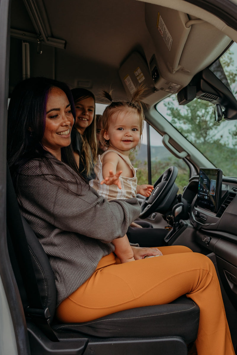 Smiling mom holds a baby with another child in their cozy rv rental, ready for family adventures. — photo 2