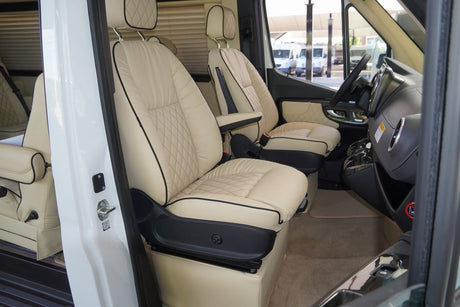 Luxurious RV rental interior showcasing quilted cream leather passenger and driver seats. Enjoy comfort on your camper van trip.