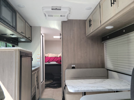 Bright, modern RV rental interior featuring a full kitchen, dining area, and rear bedroom. Perfect for family adventures.