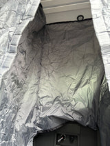 RV rental interior showing gray crinkled privacy fabric, an overhead light, and utility panel with controls.