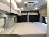 Interior view of an rv rental's sleeping area with a bed, sleek overhead cabinets, and a ceiling AC unit.