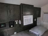 Compact RV rental interior featuring dark wood cabinets, AC, heater, and a comfy bed area.