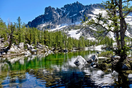 Experience breathtaking mountain landscapes! This vibrant alpine lake, surrounded by trees & snow-capped peaks, awaits your RV rental journey.