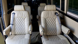 Plush, cream leather captain's chairs inside a luxurious RV rental, offering comfortable seating with diamond quilting.