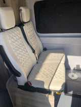 RV rental interior features white quilted passenger seats, a dark window, and a floor mount in a camper van.