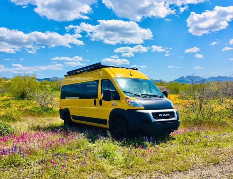 Explore nature! This bright yellow RV rental is nestled in a vibrant field of wildflowers under a clear blue sky. — photo 9