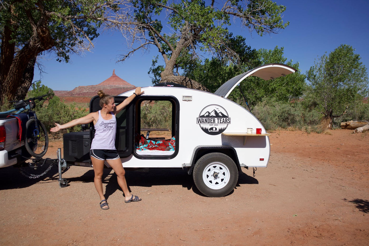 Happy woman with an RV rental teardrop camper in a desert. Perfect for outdoor camping and travel adventures. — photo 9