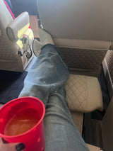 Legs up, relaxing in a comfortable rv rental. Beige quilted seating, white boots, and a red cup of juice.