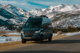Explore snowy mountains with this dark gray Mercedes-Benz Sprinter van, ideal for RV rental adventures.