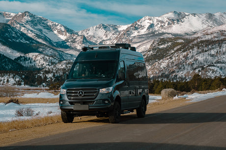 Explore snowy mountains with this dark gray Mercedes-Benz Sprinter van, ideal for RV rental adventures.